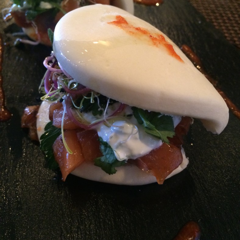 Bao de salmón ahumado con cilantro, brotes variados, cebolla roja encurtida y tzaziki