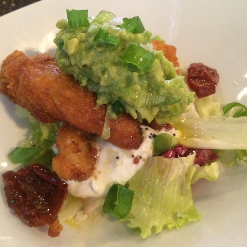 Ensalada de pollo picante y crujiente con mousse de aguacate, tomate seco y una ligera salsa de yogur con ralladura de limón y semillas de amapola