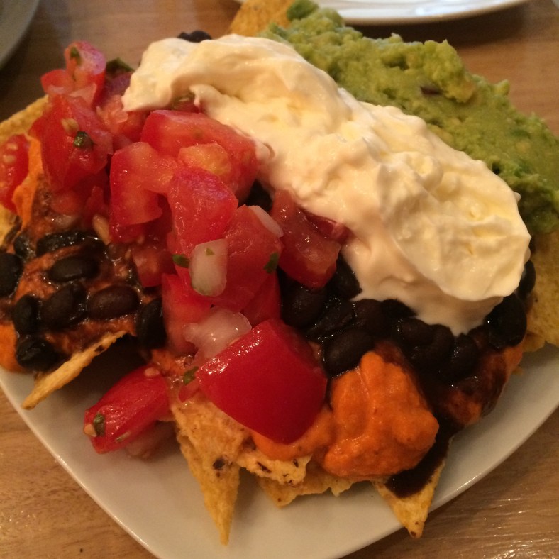 Nachos con guacamole, crema agria, frijoles, pico de gallo y salsa de cheddar