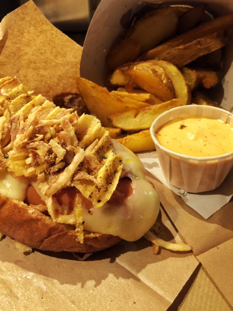 Perro Clásico: pan de cerveza negra, salchicha Bockwurst, queso emmental fundido y crujiente.